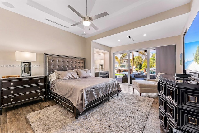 bedroom featuring a tray ceiling, access to exterior, and dark hardwood / wood-style floors