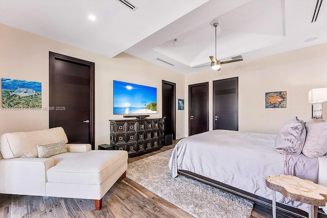 bedroom with a tray ceiling, ceiling fan, and wood-type flooring