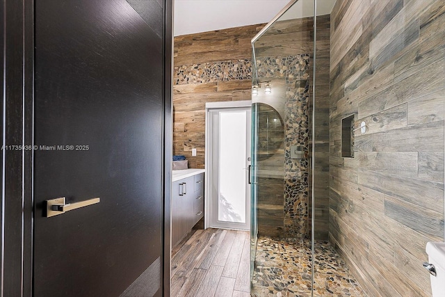 bathroom with wooden walls, vanity, a shower with door, and hardwood / wood-style floors