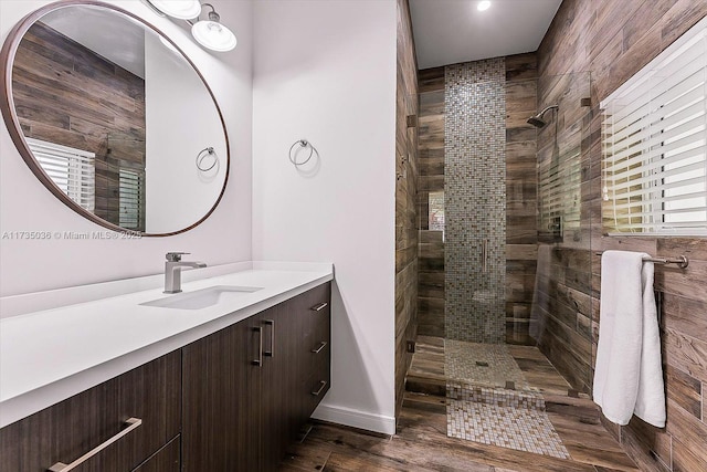 bathroom featuring vanity, wood-type flooring, and a tile shower