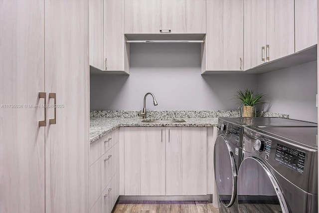 washroom featuring sink, hardwood / wood-style flooring, washing machine and dryer, and cabinets