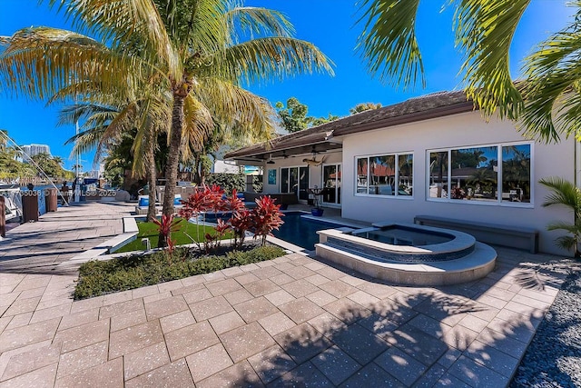 view of patio / terrace with ceiling fan and a pool with hot tub