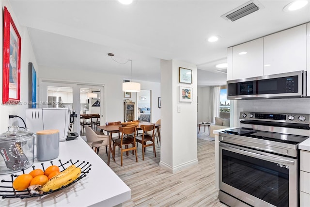 kitchen with pendant lighting, stainless steel appliances, light hardwood / wood-style floors, and white cabinets