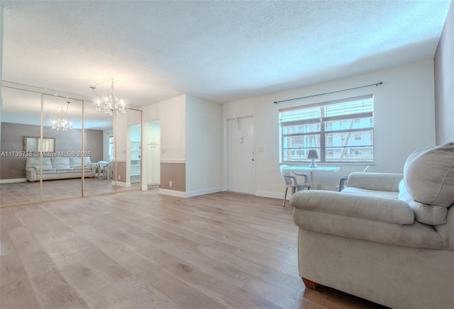 living room with a textured ceiling, light hardwood / wood-style flooring, and a notable chandelier