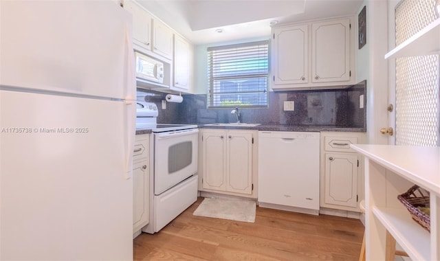 kitchen with sink, white appliances, white cabinetry, light hardwood / wood-style floors, and decorative backsplash