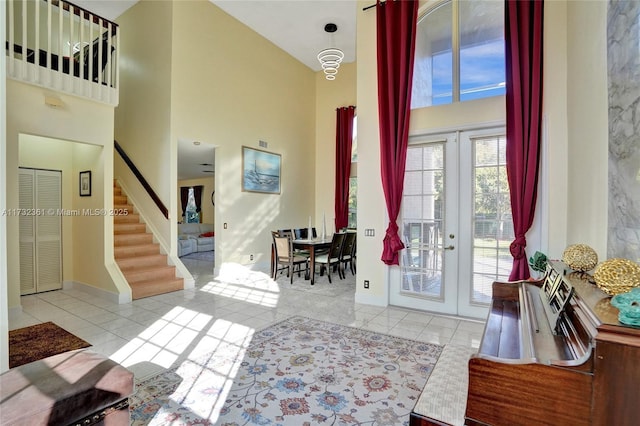 foyer featuring french doors, a towering ceiling, and light tile patterned floors