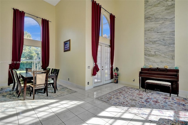 dining space with light tile patterned flooring, a towering ceiling, and french doors