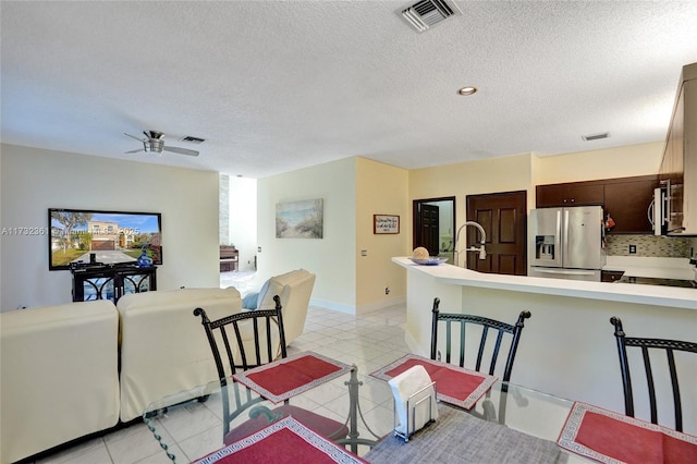 dining area with ceiling fan, sink, a textured ceiling, and light tile patterned flooring