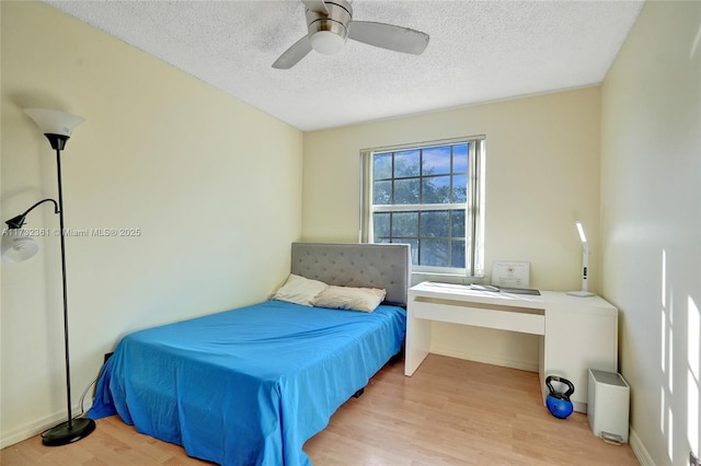 bedroom featuring ceiling fan, light hardwood / wood-style floors, and a textured ceiling