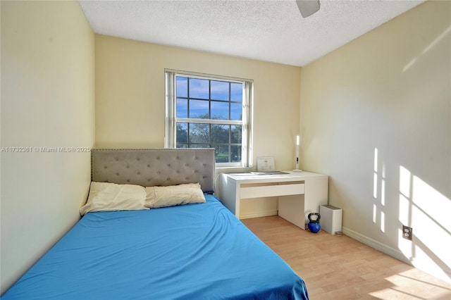 bedroom featuring ceiling fan, light hardwood / wood-style floors, and a textured ceiling