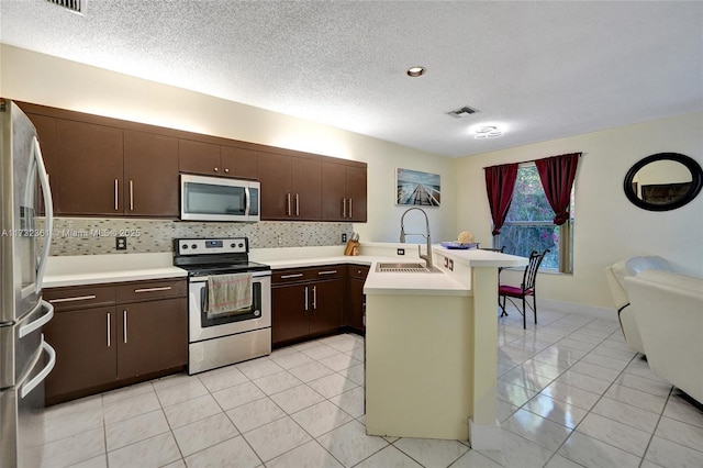 kitchen with tasteful backsplash, sink, kitchen peninsula, stainless steel appliances, and dark brown cabinets