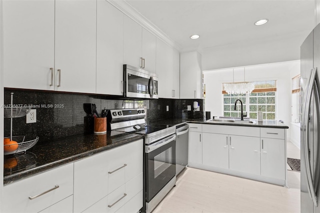 kitchen featuring sink, white cabinetry, dark stone countertops, stainless steel appliances, and decorative backsplash