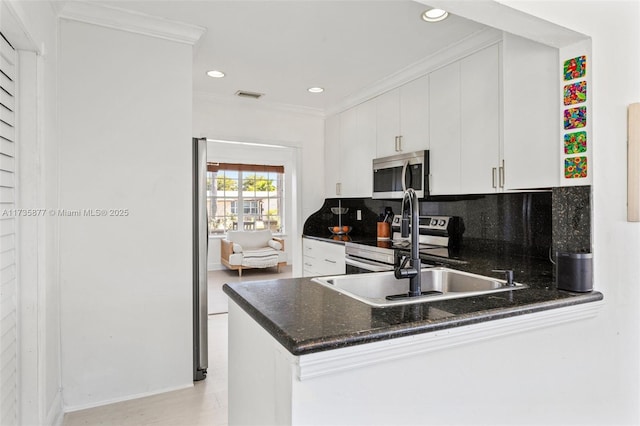 kitchen with white cabinetry, ornamental molding, kitchen peninsula, and appliances with stainless steel finishes