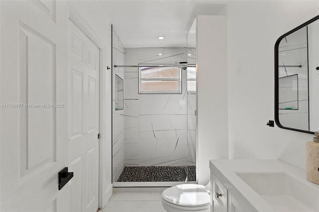 bathroom with a tile shower, vanity, and toilet