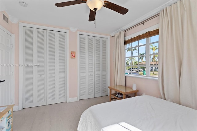 bedroom with multiple closets, ceiling fan, and light hardwood / wood-style floors