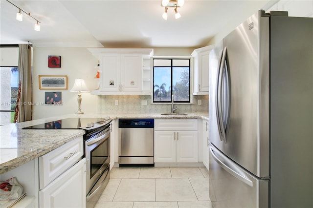 kitchen with appliances with stainless steel finishes, tasteful backsplash, sink, white cabinets, and light stone countertops