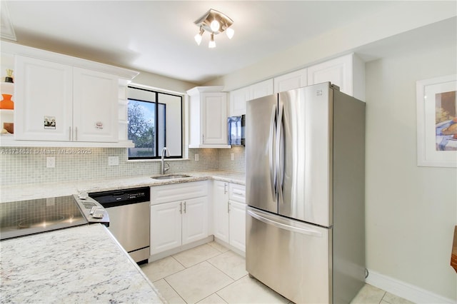 kitchen featuring light tile patterned flooring, sink, white cabinetry, stainless steel appliances, and backsplash