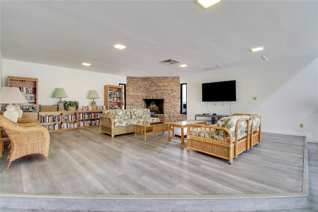 living room with a brick fireplace and light hardwood / wood-style flooring