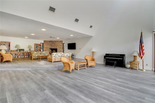 living room with a towering ceiling, a large fireplace, and light wood-type flooring