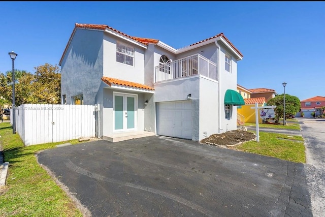 mediterranean / spanish home with a garage, french doors, and a balcony