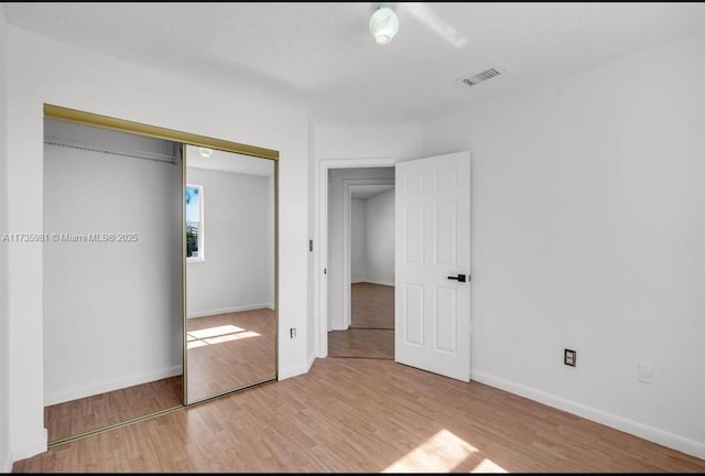 unfurnished bedroom featuring light hardwood / wood-style floors and a closet