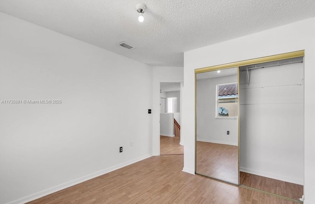 unfurnished bedroom with light hardwood / wood-style floors, a closet, and a textured ceiling