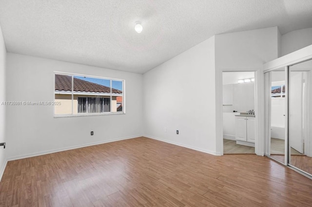 unfurnished bedroom with wood-type flooring, ensuite bathroom, and a textured ceiling