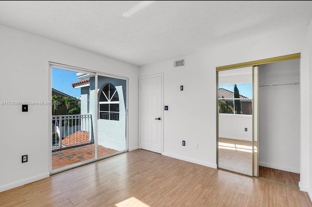 interior space with hardwood / wood-style flooring, a textured ceiling, access to exterior, and multiple windows