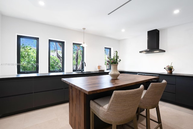 kitchen with range hood, sink, wooden counters, hanging light fixtures, and a center island