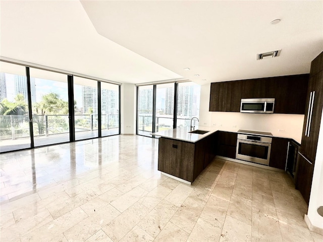 kitchen with visible vents, a sink, open floor plan, appliances with stainless steel finishes, and a peninsula