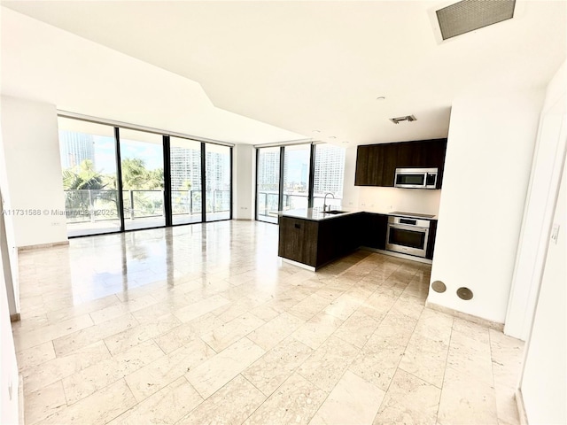 kitchen featuring an island with sink, appliances with stainless steel finishes, sink, and dark brown cabinets