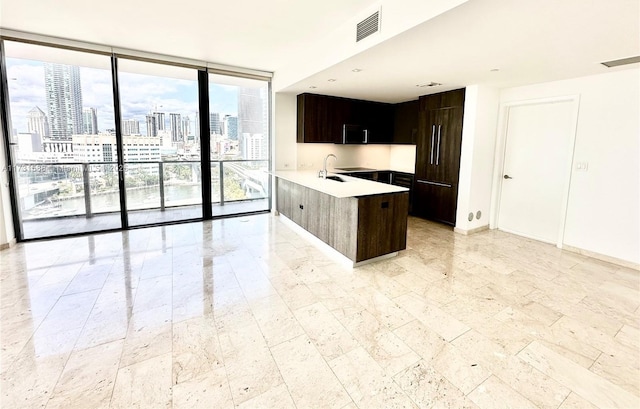 kitchen with dark brown cabinetry, floor to ceiling windows, kitchen peninsula, and sink