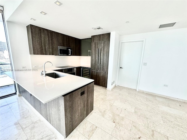 kitchen featuring plenty of natural light, sink, a kitchen bar, and kitchen peninsula