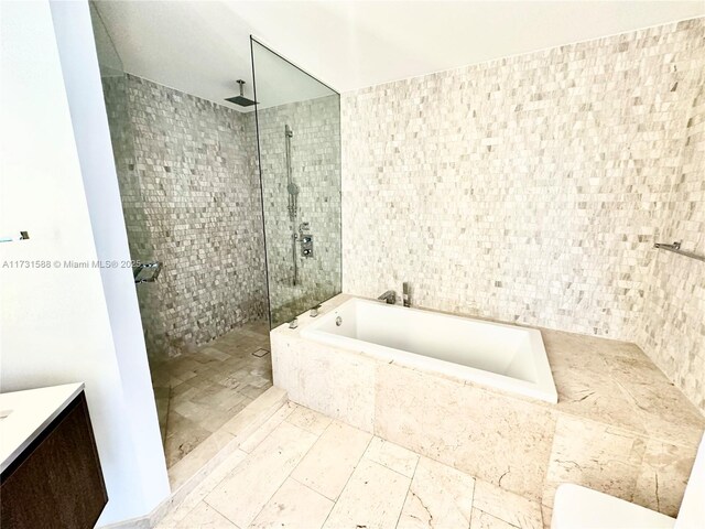 bathroom featuring vanity, shower with separate bathtub, and tile walls