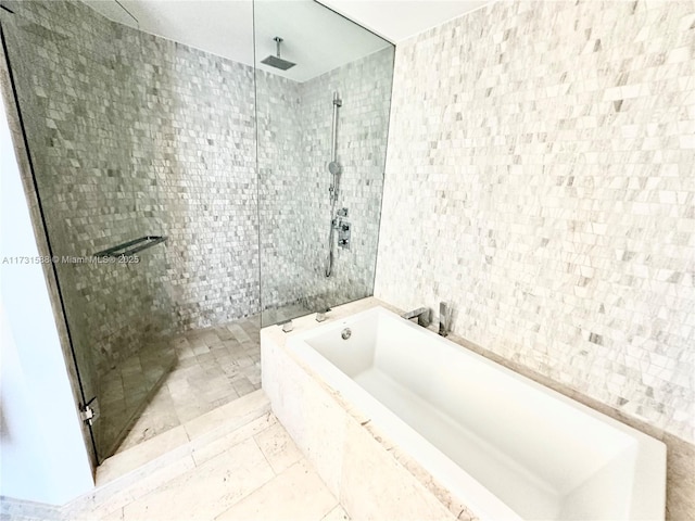 bathroom featuring shower with separate bathtub and tile walls