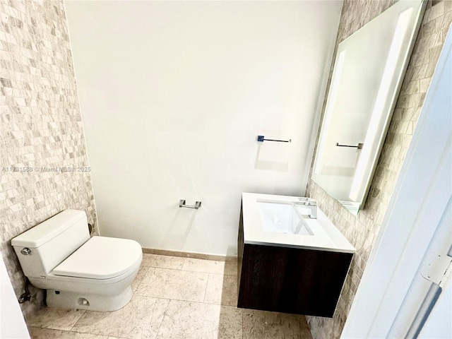 bathroom with vanity, toilet, and tile walls