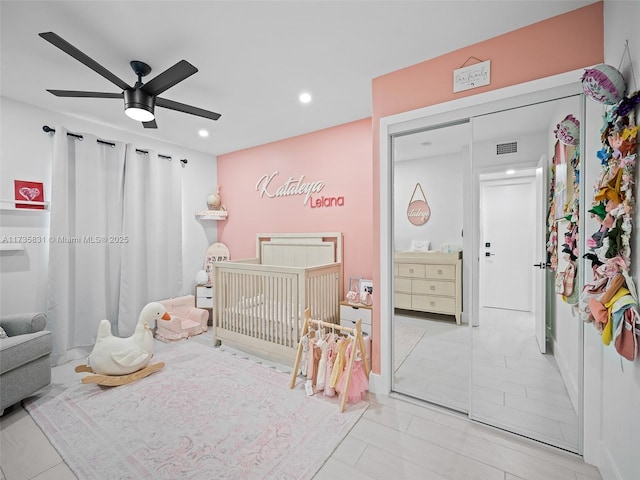 bedroom with a nursery area and ceiling fan