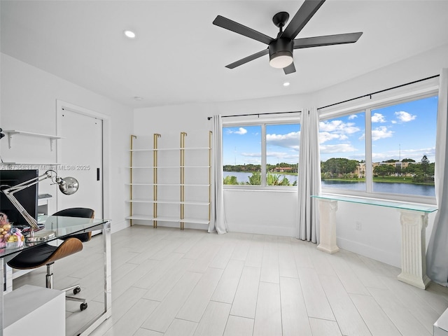 office area with a water view, ceiling fan, and light wood-type flooring