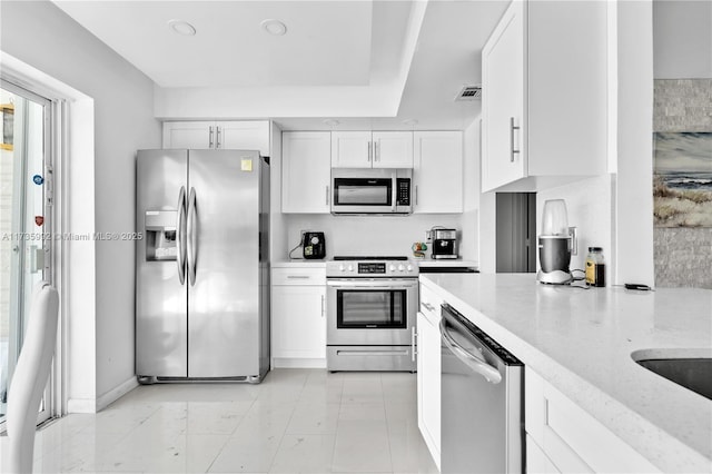 kitchen with white cabinetry, light stone countertops, and stainless steel appliances