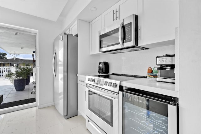 kitchen with white cabinetry, stainless steel appliances, beverage cooler, and decorative backsplash