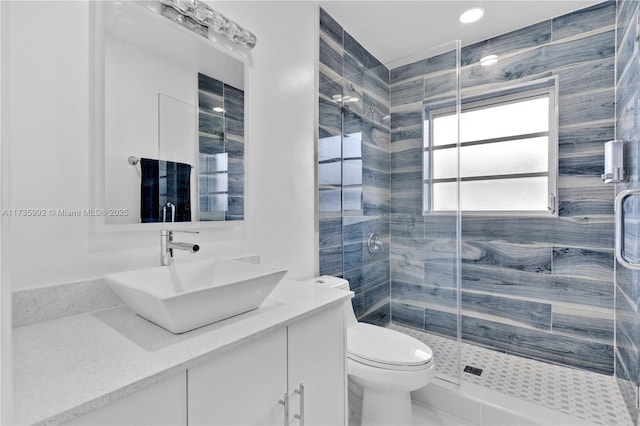 bathroom with vanity, a shower with door, and toilet