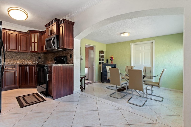 kitchen featuring dark stone counters, black range with electric stovetop, light tile patterned floors, and backsplash