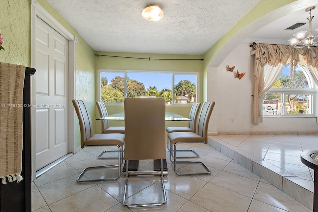 dining area featuring light tile patterned floors, plenty of natural light, and a textured ceiling