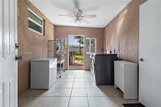 clothes washing area featuring ceiling fan, light tile patterned floors, washing machine and clothes dryer, and a textured ceiling