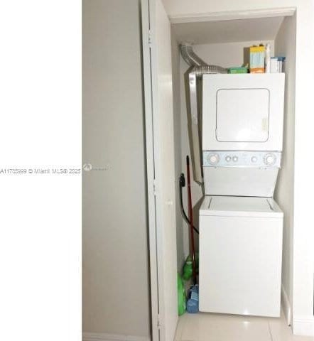 laundry room featuring light tile patterned floors and stacked washing maching and dryer