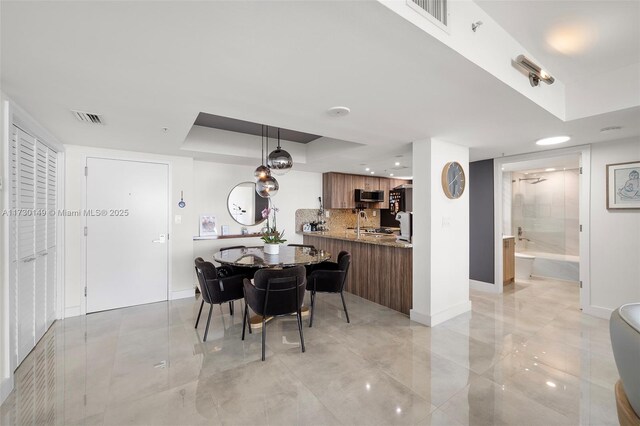 dining space with a tray ceiling and sink