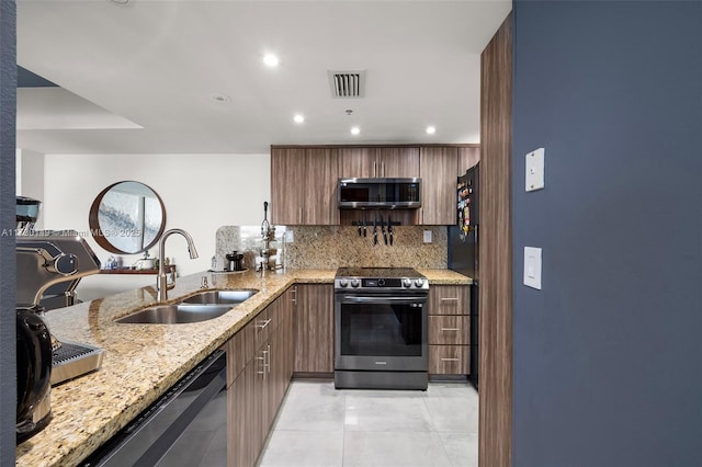 kitchen featuring sink, stainless steel appliances, light stone counters, decorative backsplash, and kitchen peninsula