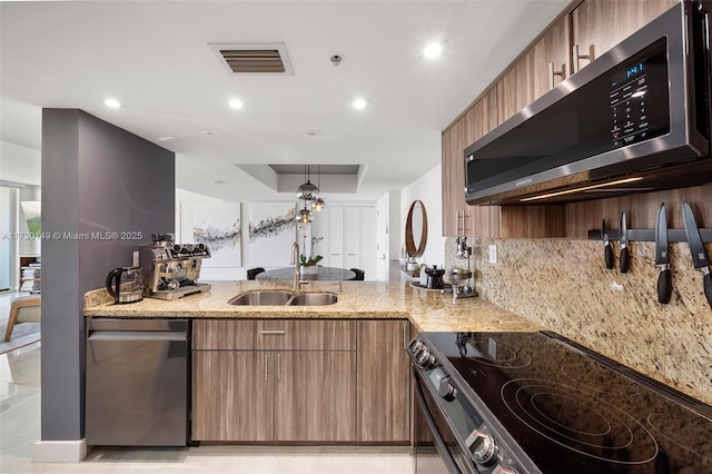 kitchen featuring appliances with stainless steel finishes, tasteful backsplash, sink, hanging light fixtures, and light stone counters