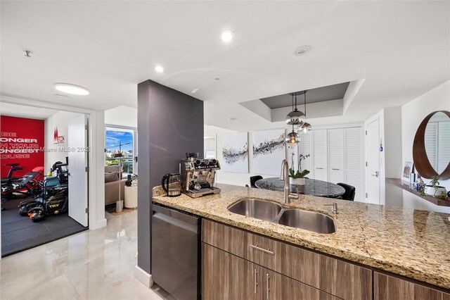 kitchen with sink, a tray ceiling, light stone countertops, and dishwasher