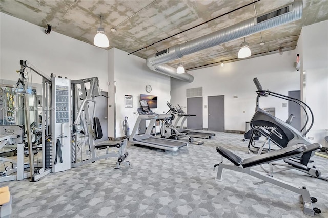 exercise room with a towering ceiling and carpet